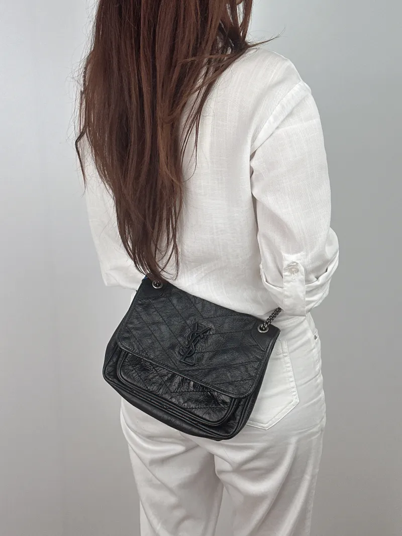 SAINT LAURENT Crossbody Bag Niki Black Waxed Leather Calfskin Small 21 × 7.5 × 16 cm — on-model view 1 of 2