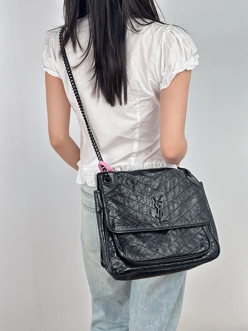 SAINT LAURENT Crossbody Bag Niki Black Waxed Leather Calfskin Large 32 × 9 × 23 cm — on-model view 1 of 3